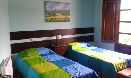 Habitación con 2 camas y una pintura en la pared. en Casa Rural de alquiler integro La Cantina de Villarmayor-Asturias, en Villarmayor