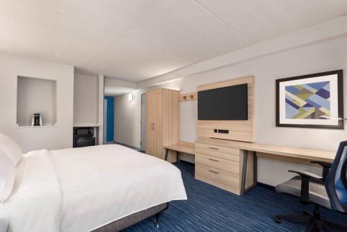 a hotel room with a bed and a desk with a television at Holiday Inn Express Dumfries-Quantico by IHG in Dumfries