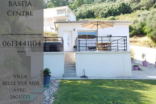 a house with a balcony with an umbrella at Villa du Macchione BASTIA by Location-tourisme-corse in Bastia