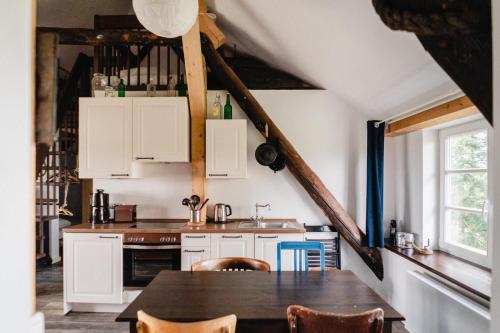 a kitchen with white cabinets and a table with chairs at Haus Anna Elbe, Bauernhaus-Ferienwohnungen an der Elbe in Hamburg