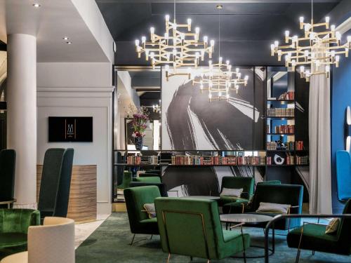 a waiting room with green chairs and a chandelier at Century Old Town Prague - MGallery Collection in Prague