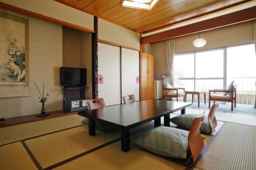 a living room with a table and chairs at Tabinoyado Ushionoakari Geiboso in Shima
