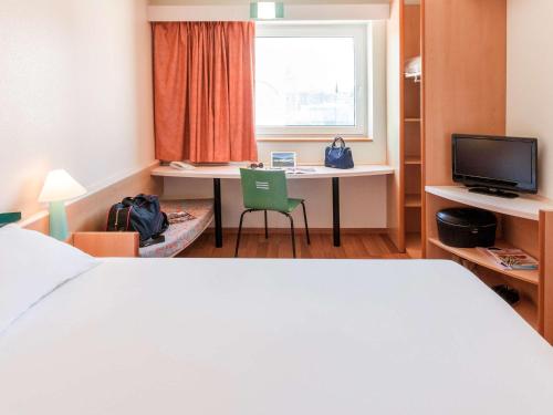 a hotel room with a bed and a desk and a window at Ibis Murcia in Murcia