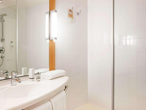 a white bathroom with a sink and a shower at Ibis Ripollet in Ripollet