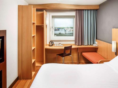 a hotel room with a bed and a desk and a window at ibis Aberdeen Centre – Quayside in Aberdeen