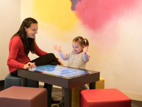a woman and a little girl sitting at a table at Novotel Suites Paris Stade de France in Saint-Denis