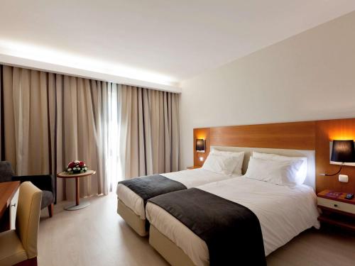 Hotel Mercure Lisboa في لشبونة: غرفة الفندق بسرير كبير ومكتب