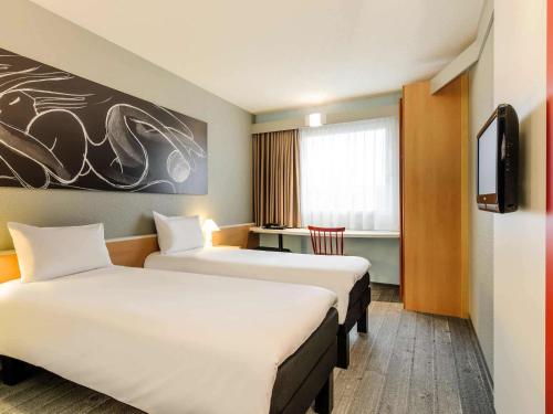 ein Hotelzimmer mit 2 Betten und einem TV in der Unterkunft ibis Hotel Hannover City in Hannover