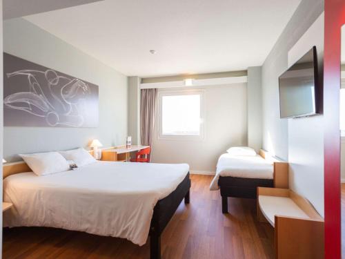 Una habitación de hotel con dos camas y un televisor. en Ibis Elche, en Elche