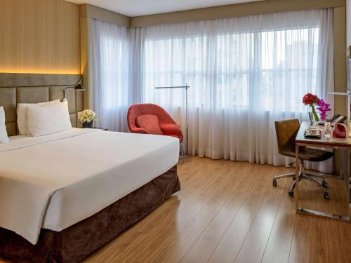 um quarto de hotel com uma cama grande e uma secretária em Mercure Sao Paulo Jardins em São Paulo