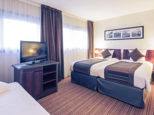 a hotel room with two beds and a flat screen tv at Mercure Tours Centre Gare et Congrès in Tours