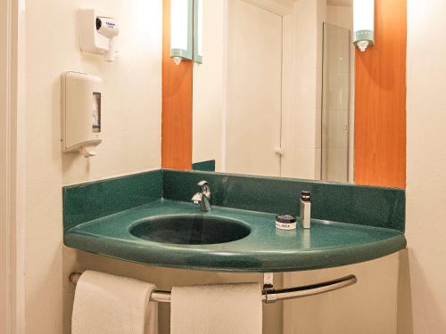 La salle de bains est pourvue d'un lavabo vert et d'un miroir. dans l'établissement Ibis Monterrey Valle, à Monterrey