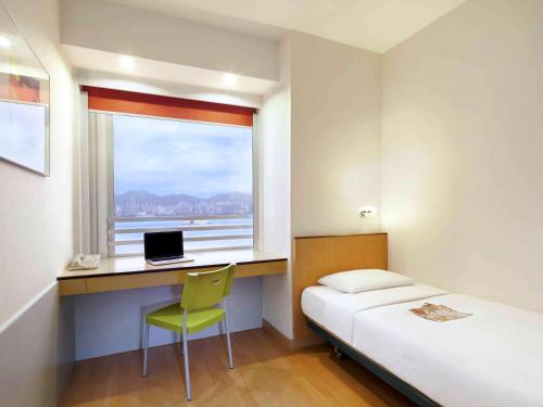 a bedroom with a bed and a desk with a laptop at ibis Hong Kong North Point in Hong Kong
