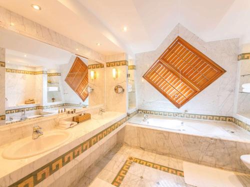 a large bathroom with two sinks and a tub and a large window at Oryx Grand Hotel Jebel Hafeet in Al Ain