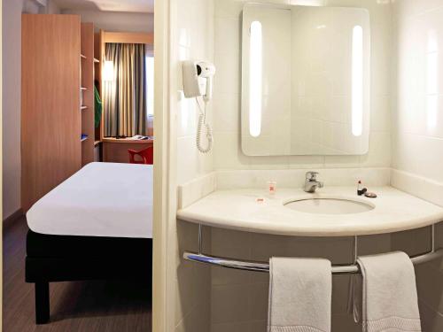 a bathroom with a sink and a bed and a mirror at ibis Goiânia in Goiânia