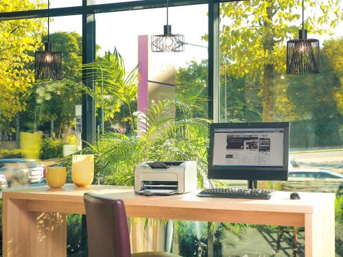 a desk with a computer and a printer on it at Mercure Hotel Plaza Essen in Essen