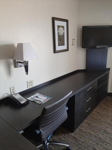 a desk in a hotel room with a telephone and a television at Candlewood Suites Aurora-Naperville by IHG in Aurora