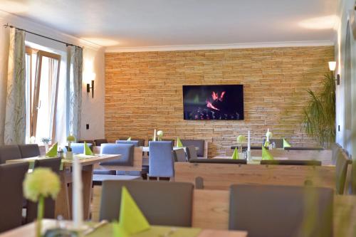 a restaurant with tables and chairs and a tv on a brick wall at Gästehaus Bärwald in Seeboden