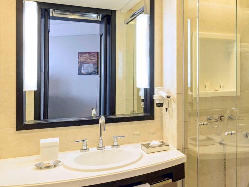 La salle de bains est pourvue d'un lavabo et d'une douche en verre. dans l'établissement Novotel Florianopolis, à Florianópolis