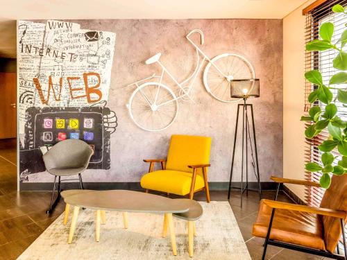 a room with two chairs and a wall with bikes at ibis Marne La Vallée Val d'Europe in Montévrain