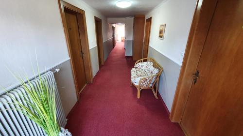 a hallway with a chair and a red carpet at Gästehaus Bärwald in Seeboden