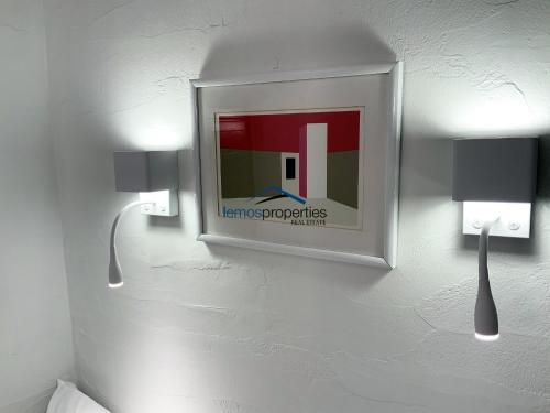 a picture hanging on a wall with two lights at Aqua Blue, only 100 meters from the beach of Gialiskari in Ioulida