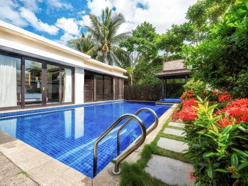 a swimming pool in front of a house at Pullman Sanya Yalong Bay Villas & Resort in Sanya