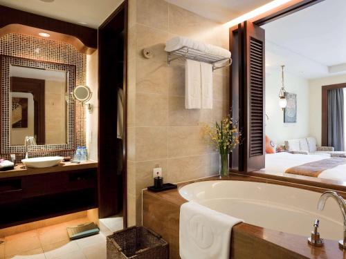 a bathroom with a bath tub and a bed at Pullman Sanya Yalong Bay Villas & Resort in Sanya