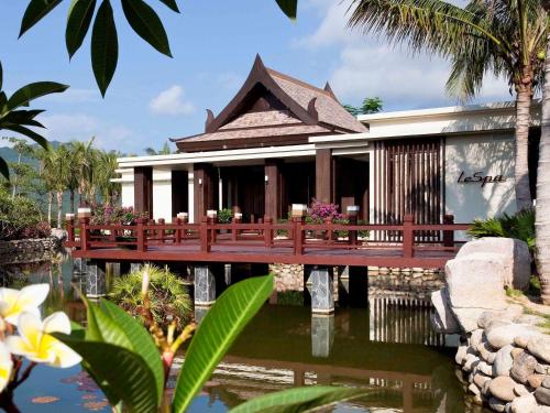 a house with a wooden bridge over a pond at Pullman Sanya Yalong Bay Villas & Resort in Sanya