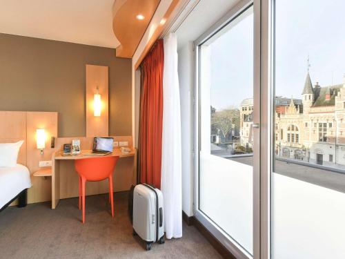 a hotel room with a bed and a desk and a window at ibis Kortrijk Centrum in Kortrijk