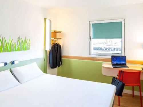 a bedroom with a bed and a desk with a laptop at ibis budget Leicester in Leicester