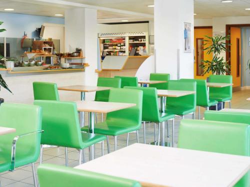 a cafeteria with tables and green chairs at ibis budget Newport in Newport
