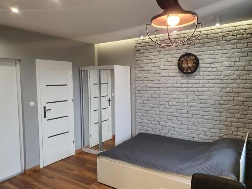a bedroom with a brick wall with a bed and a clock at Iława Apartamenty in Iława
