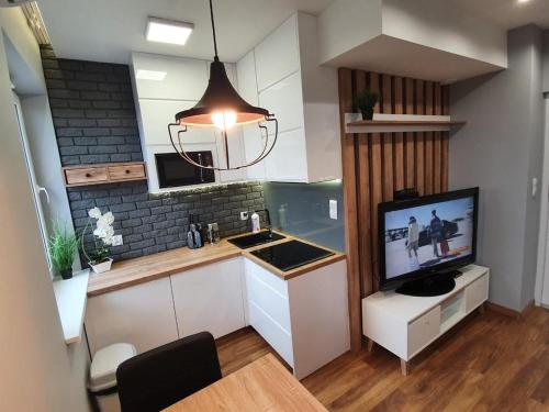 a kitchen with a television and a kitchen with a counter at Iława Apartamenty in Iława