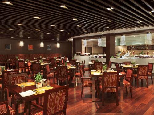 a restaurant with tables and chairs in a room at Novotel Mumbai Juhu Beach in Mumbai