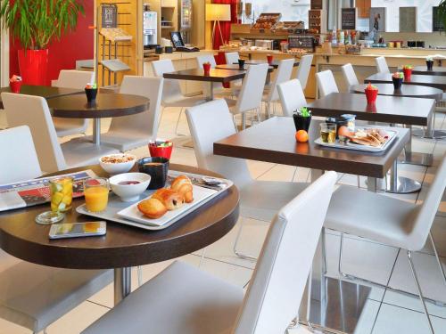 a cafeteria with tables and chairs with food on them at ibis Etampes in Étampes