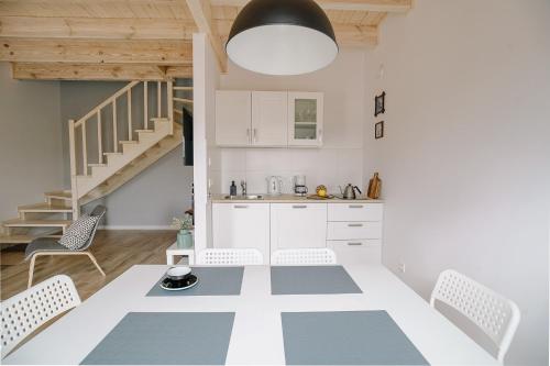 a kitchen with white cabinets and a table and chairs at Domki Kalinowa14 Kopalino in Kopalino