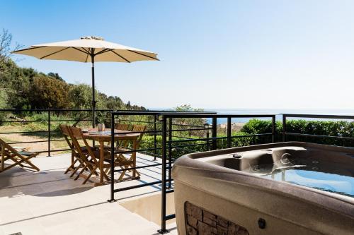 a hot tub on a balcony with a table and an umbrella at Villa du Macchione BASTIA by Location-tourisme-corse in Bastia