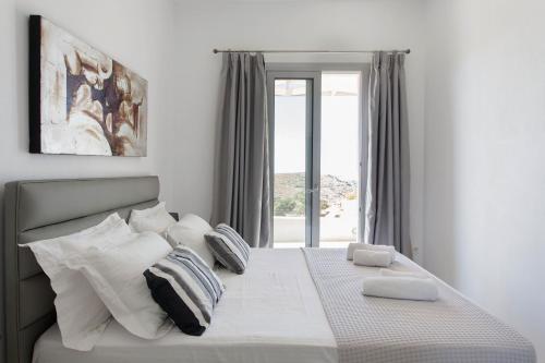 a bedroom with a white bed with a window at Kea Villa Thea- Villa Ilios in Vourkarion