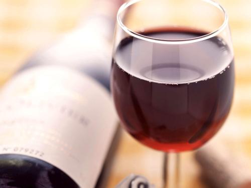 a glass of red wine next to a bottle of wine at Ibis Lleida in Lleida