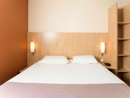 a bedroom with a large white bed with two pillows at ibis Issy les Moulineaux "Val de Seine" in Issy-les-Moulineaux