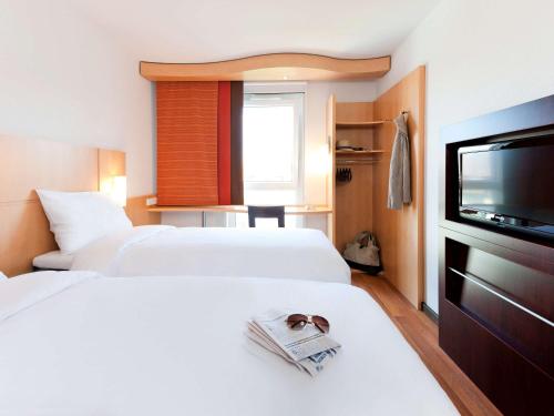 um quarto de hotel com duas camas e uma televisão de ecrã plano em ibis München City Süd em Munique