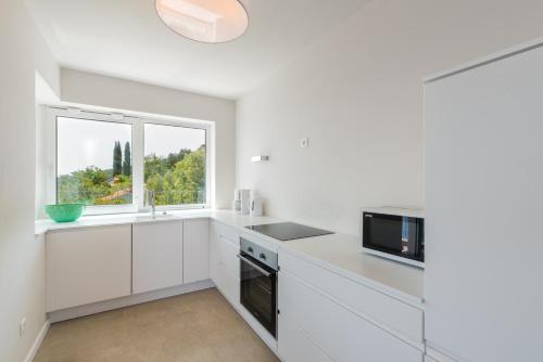 a white kitchen with white cabinets and a window at House 61 Sveta Marina in Sveta Marina