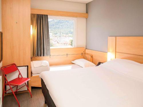 a hotel room with a large bed and a red chair at ibis Montenegro in Montenegro