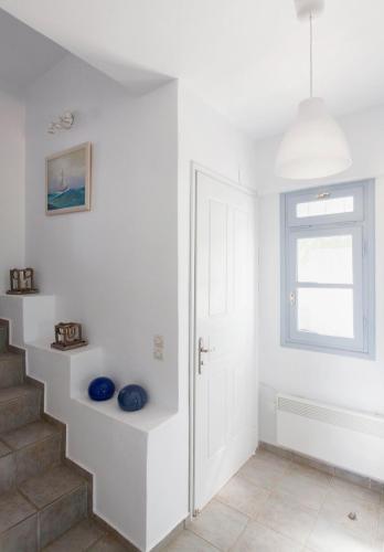 a white staircase in a white room with a window at Kea Villa Thea- Villa Ilios in Vourkarion
