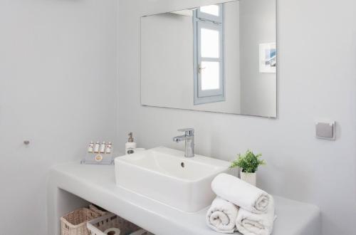a white bathroom with a sink and a mirror at Kea Villa Thea- Villa Ilios in Vourkarion