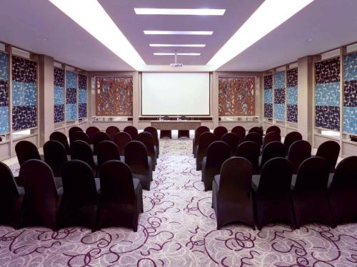 a conference room with chairs and a projection screen at Grand Mercure Bandung Setiabudi in Bandung