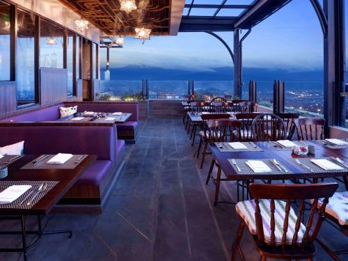 a restaurant with tables and chairs and a view at Grand Mercure Bandung Setiabudi in Bandung