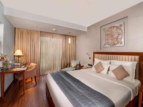 坎多林Novotel Goa Resort & Spa Candolim的配有一张大床和一张书桌的酒店房间