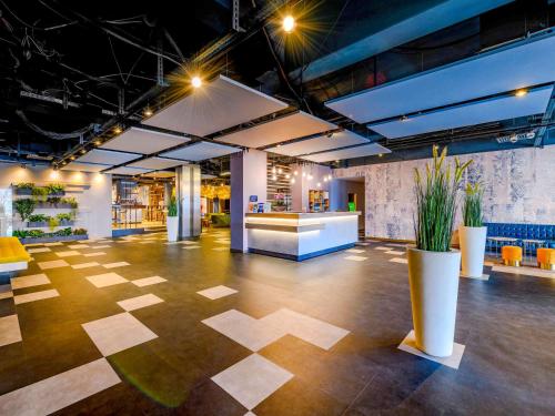 a large room with a lobby with plants and a counter at Ibis Styles Regensburg in Regensburg